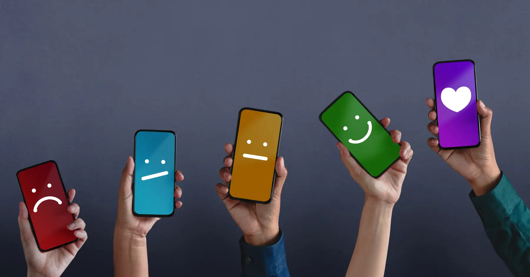 Multiple hands holding smartphones displaying different emoticon faces against a gray background.