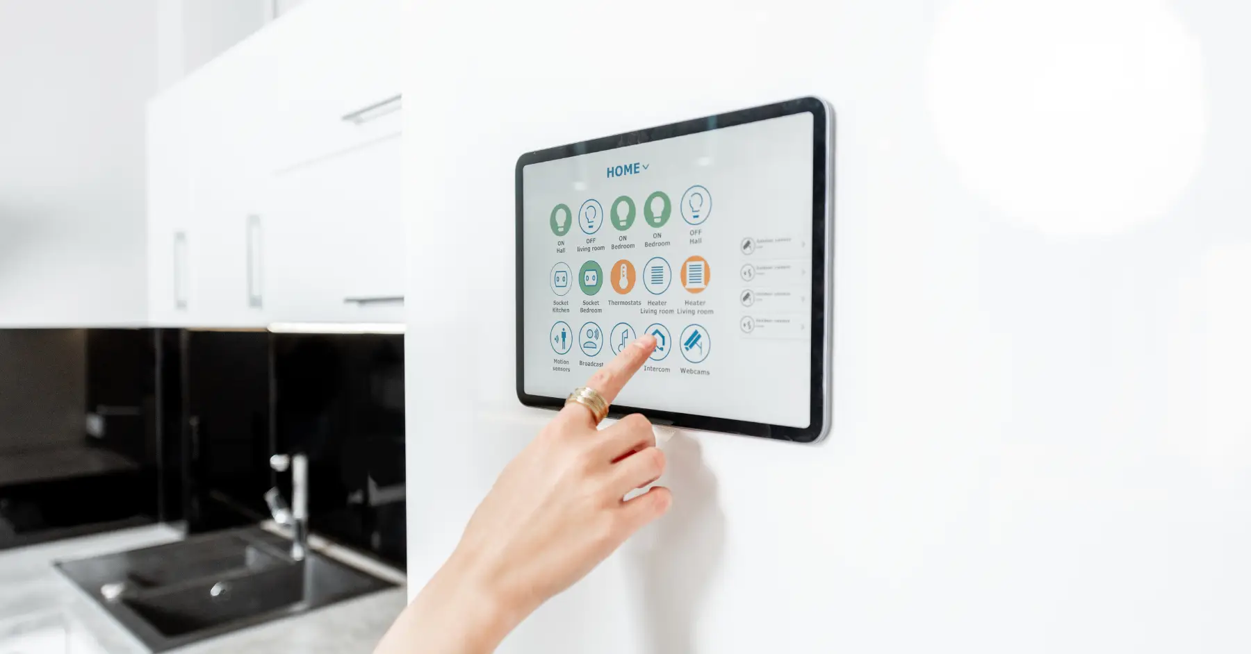 A person using a touchscreen panel on a smart home system to control various home devices.