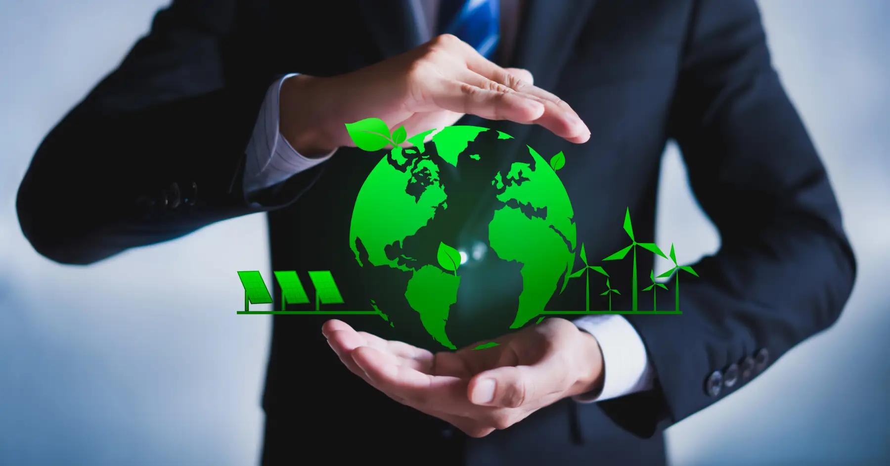 Businessman cradling a green globe with energy symbols, representing sustainable technologies in manufacturing.