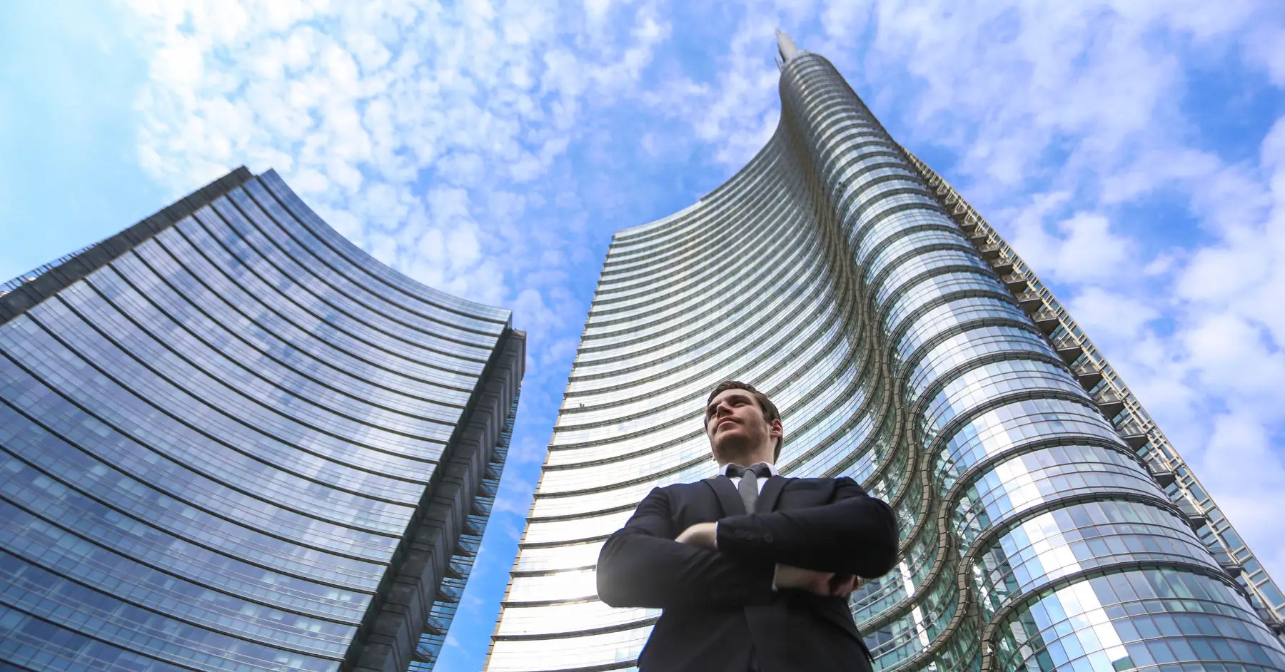 Confident businessman standing in front of modern skyscrapers, symbolizing leadership and success in the startup world.