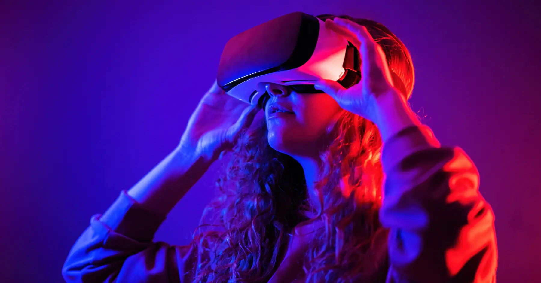 Woman experiencing virtual reality with a VR headset under vibrant purple lighting.