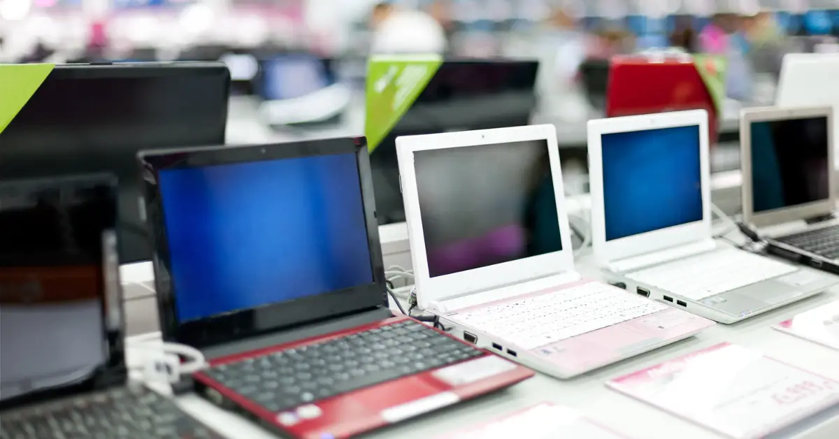 Array of laptops on display, showcasing diverse colors and sizes for consumer choice.