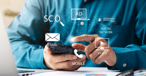 Person using a smartphone with digital marketing icons floating around, depicting SEO, email, social network, and video advertising strategies.