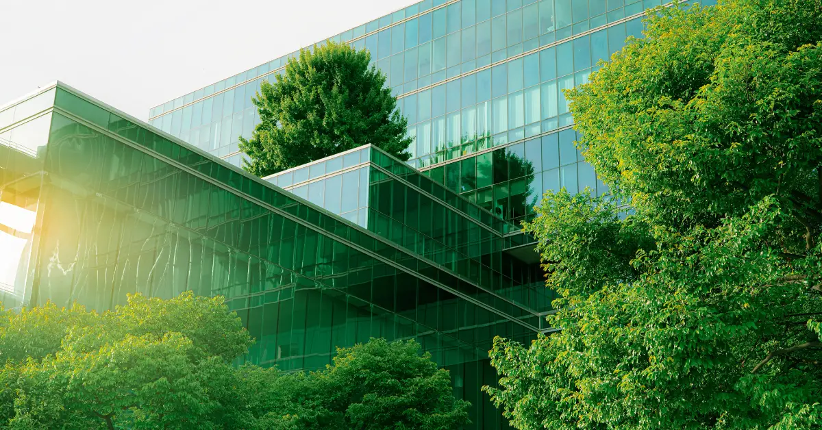 Modern office building facade covered in reflective glass and lush greenery, showcasing sustainable urban design.