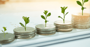 Young plants growing from coins symbolizing investment and growth over time.