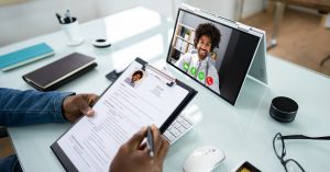 Person reviewing a resume while conducting an online video interview with a smiling candidate.