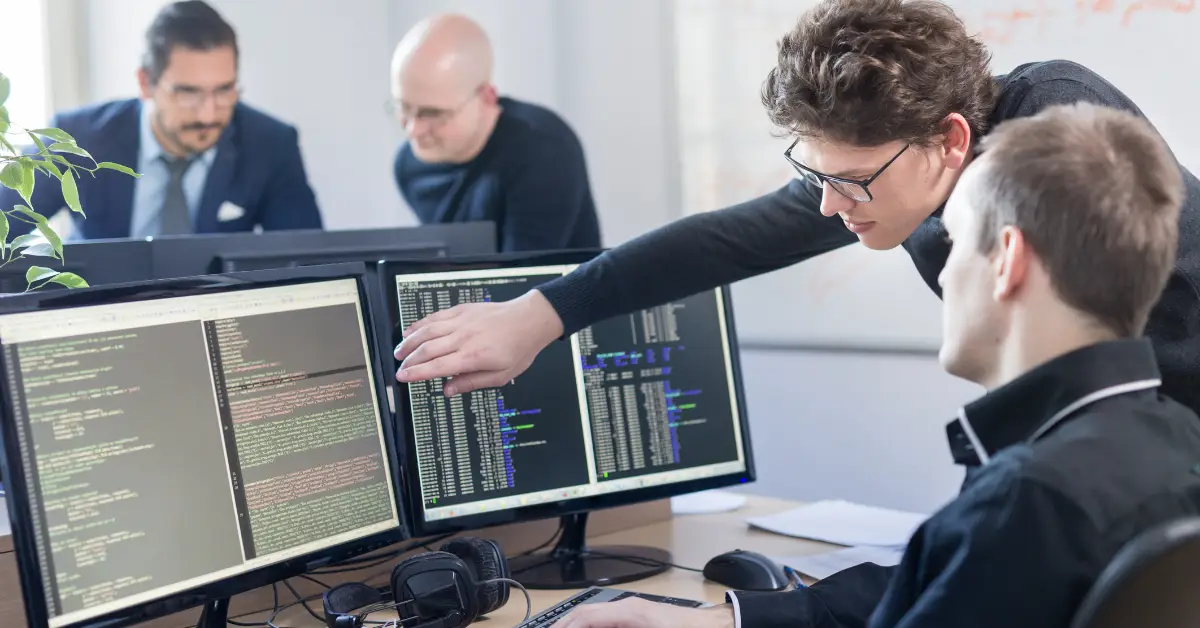 Tech startup team members collaborate on code and strategy in a modern office setting.