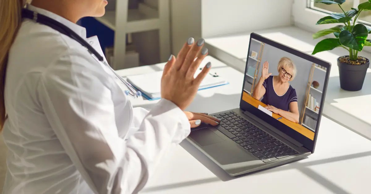 Doctor engaging in a telehealth consultation with an elderly patient via laptop.