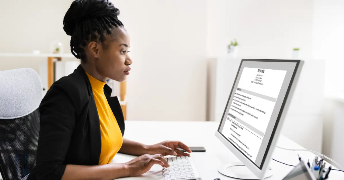Professional woman reviewing her tech resume on a computer screen in a modern office setting.