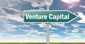 Green road sign reading 'Venture Capital' against a blue sky with clouds.