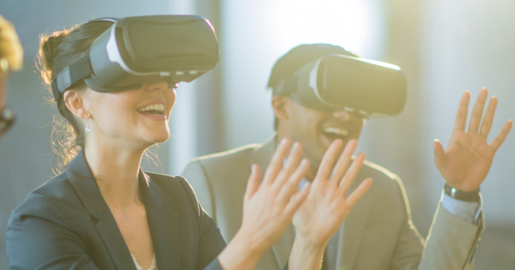 Two people wearing VR headsets and smiling, experiencing virtual reality technology in a bright, modern office setting.