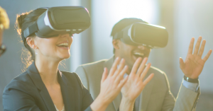 Two people wearing VR headsets and smiling, experiencing virtual reality technology in a bright, modern office setting.