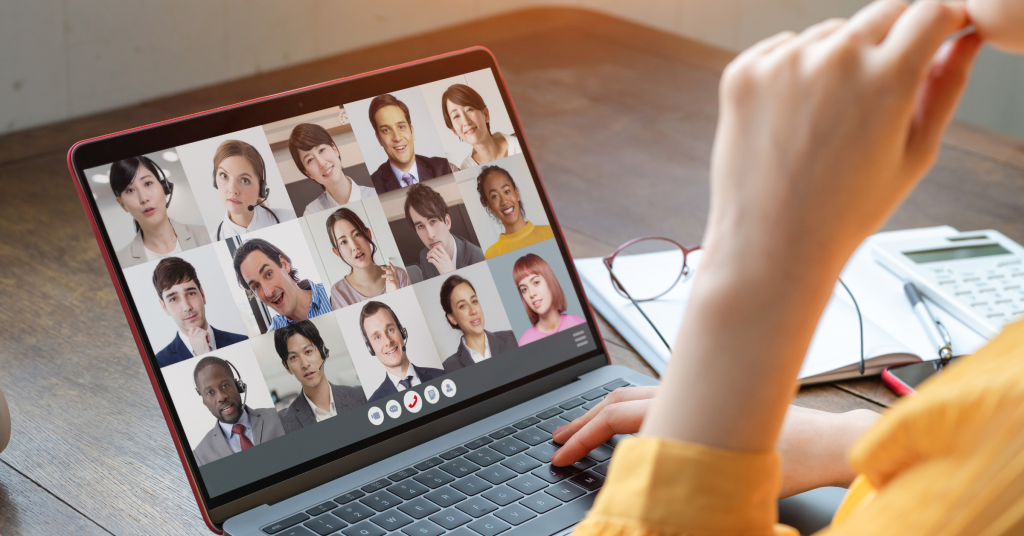 Person participating in a virtual meeting with multiple colleagues displayed on a laptop screen.